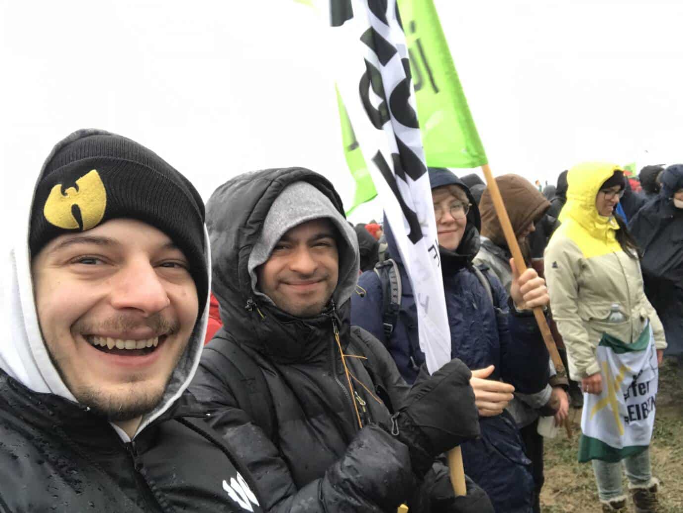 Gruppe mit Fahne bei Regen lächelnd.