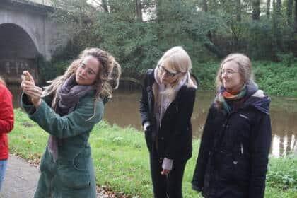 Drei Frauen am Flussufer bei einer botanischen Wanderung.