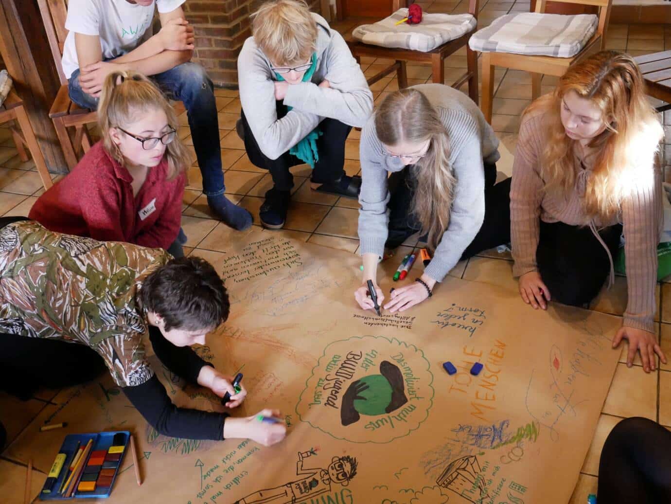 Gruppe arbeitet zusammen am Boden an einem Projekt.