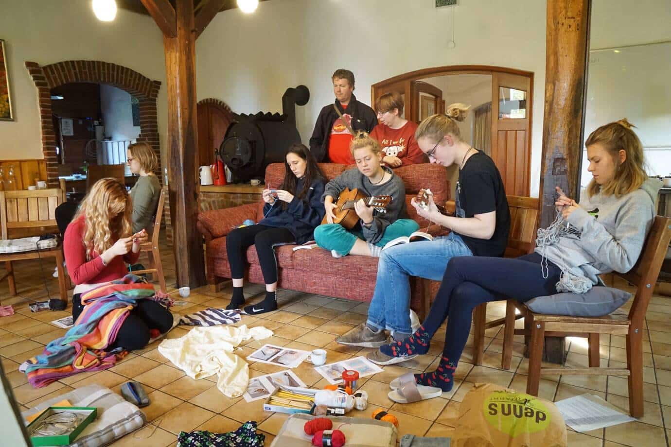 Gruppe beim Stricken und Gitarre spielen im Wohnzimmer