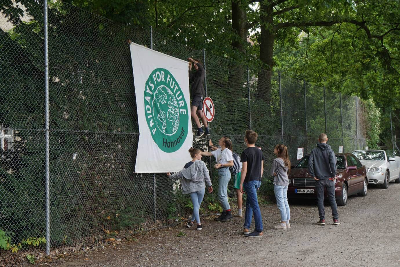 Gruppe hängt Fridays for Future Banner auf.