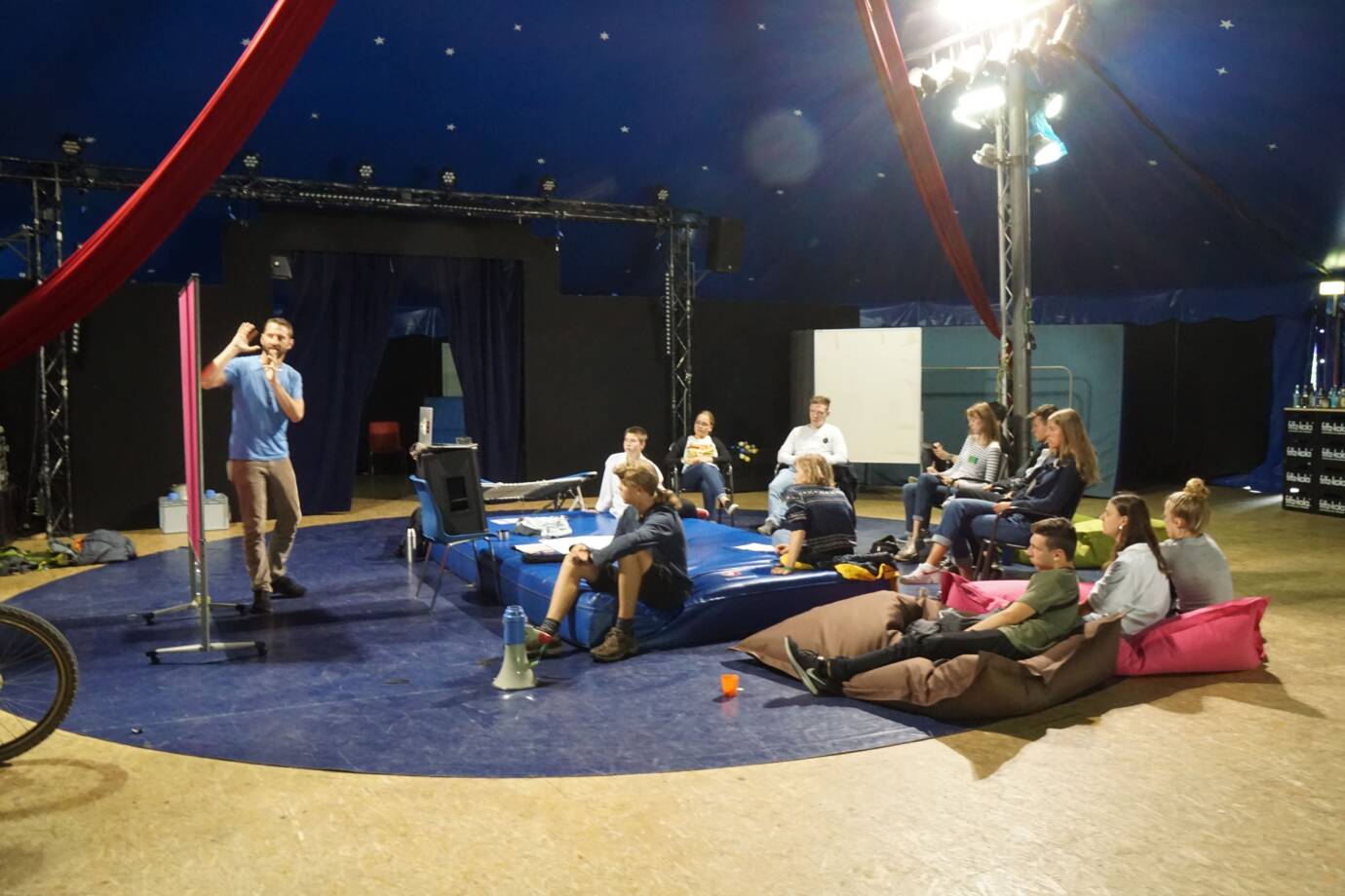Menschen sitzen in einem Zelt und hören zu.