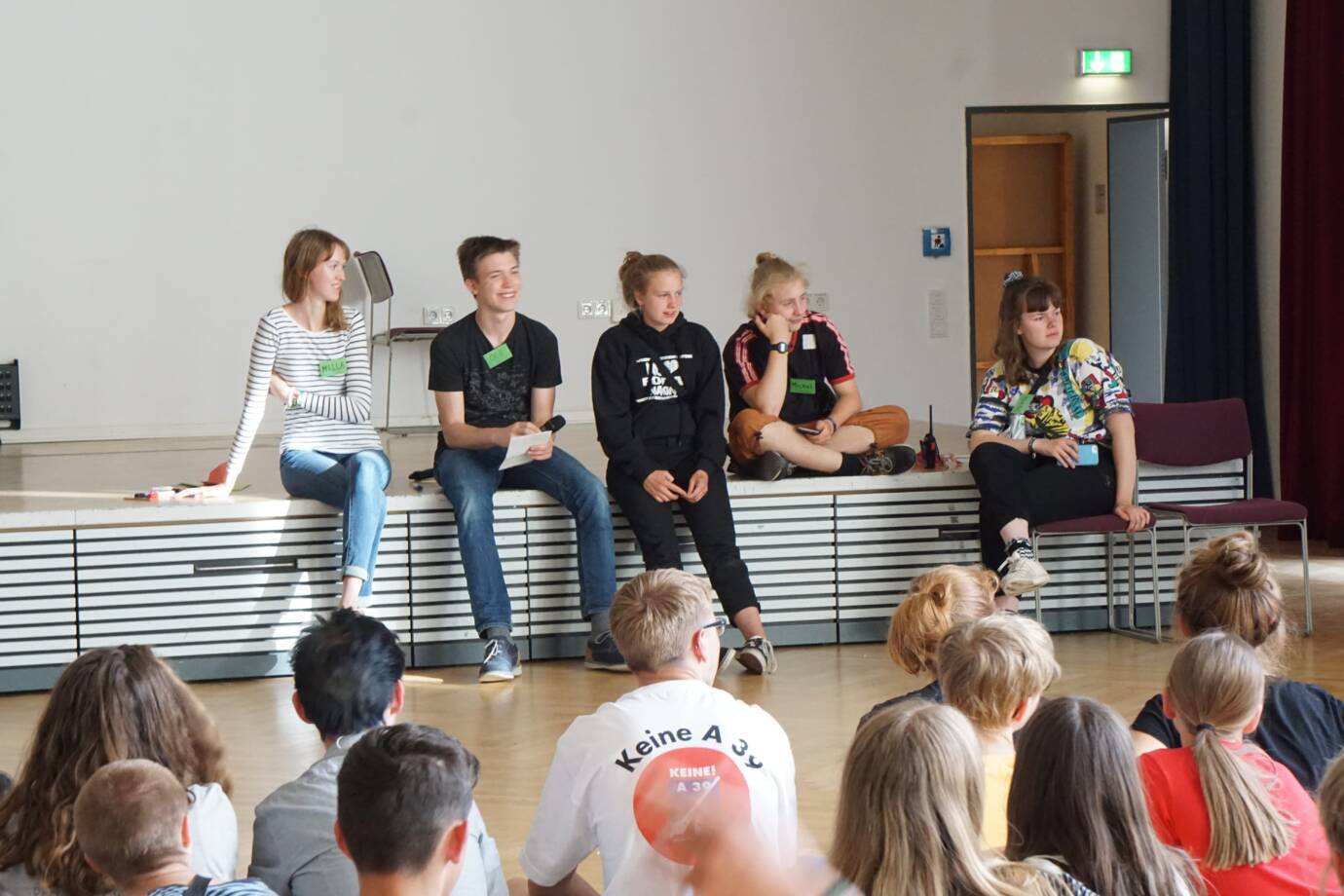 Jugendliche halten Vortrag vor Publikum in Turnhalle
