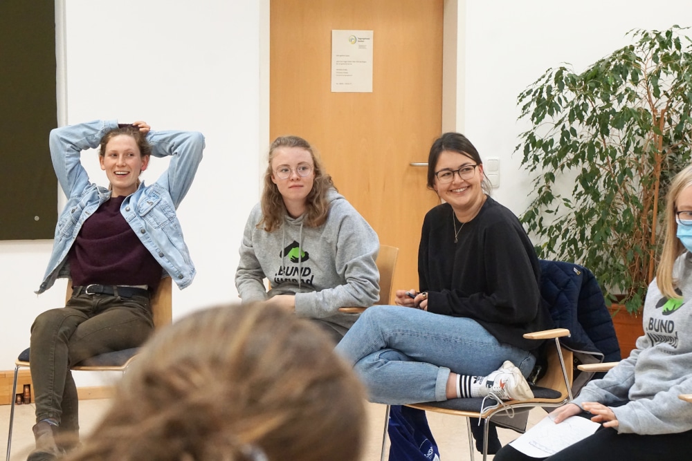 Menschen sitzen im Kreis und lächeln.