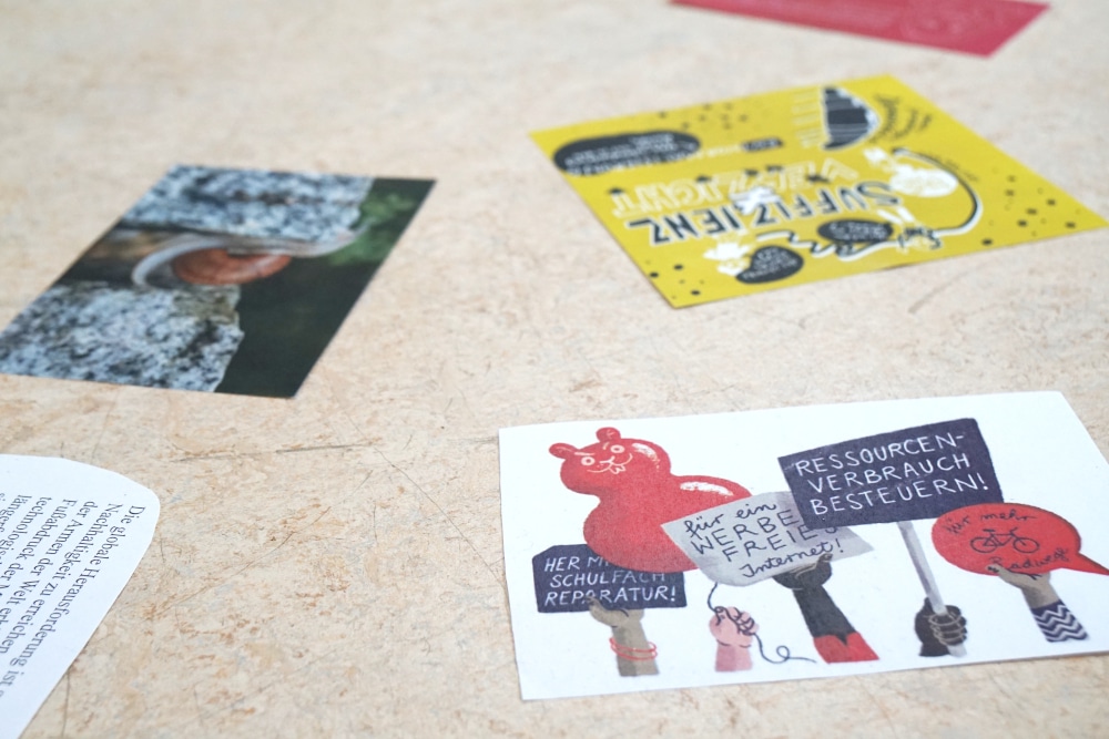 Bunte Protestplakate auf hellem Tisch verteilt.