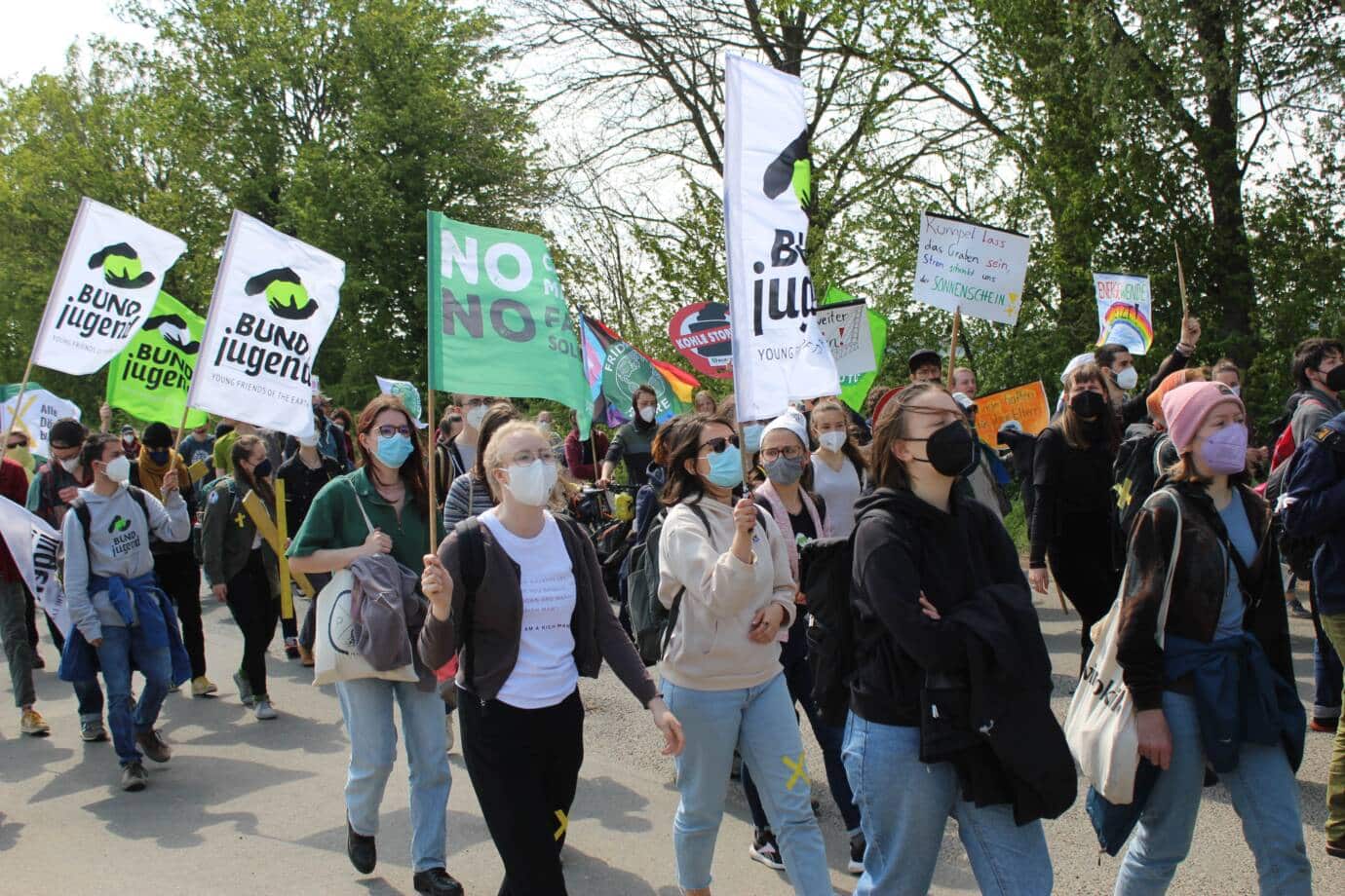 Protestierende mit Bannern und Masken bei Demonstration.
