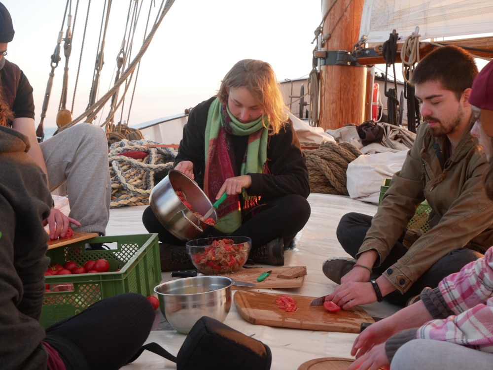 Menschen kochen zusammen auf einem Segelschiff.