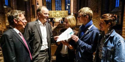 Gruppe diskutiert in einer Kirche über ein Dokument.