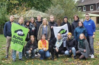 Gruppe junger Menschen mit BUND Jugend Bannern draußen.