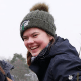 Frau mit Wintermütze im Freien lächelnd