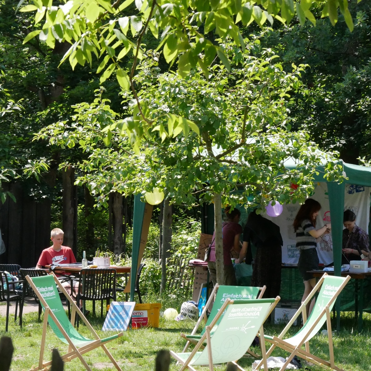 Sommerliches Gartenfest mit Menschen und Liegestühlen.