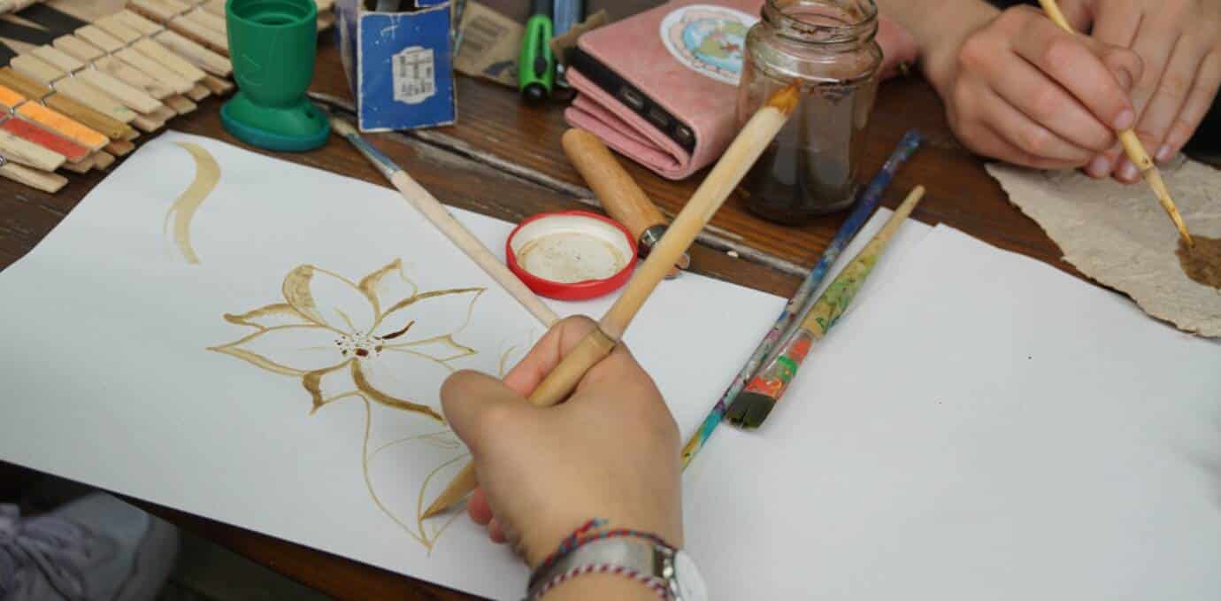 Person malt Blume auf Papier