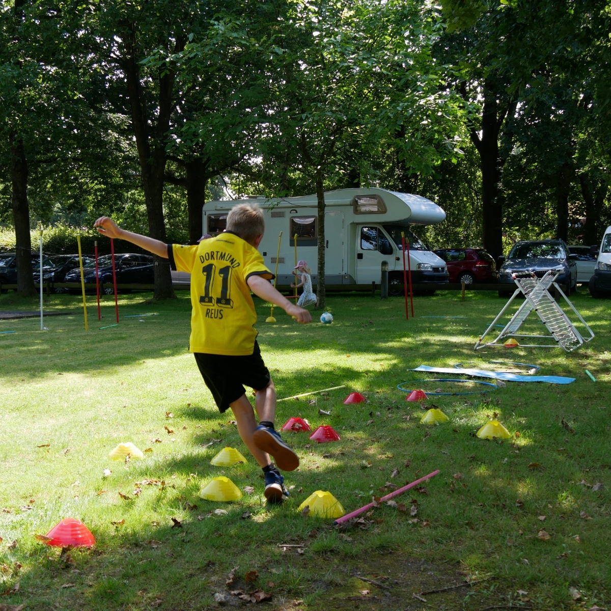 Junge spielt Draußen auf Campingplatz mit Wohnmobil.