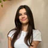 Frau mit langen Haaren und weißem Shirt lächelt.