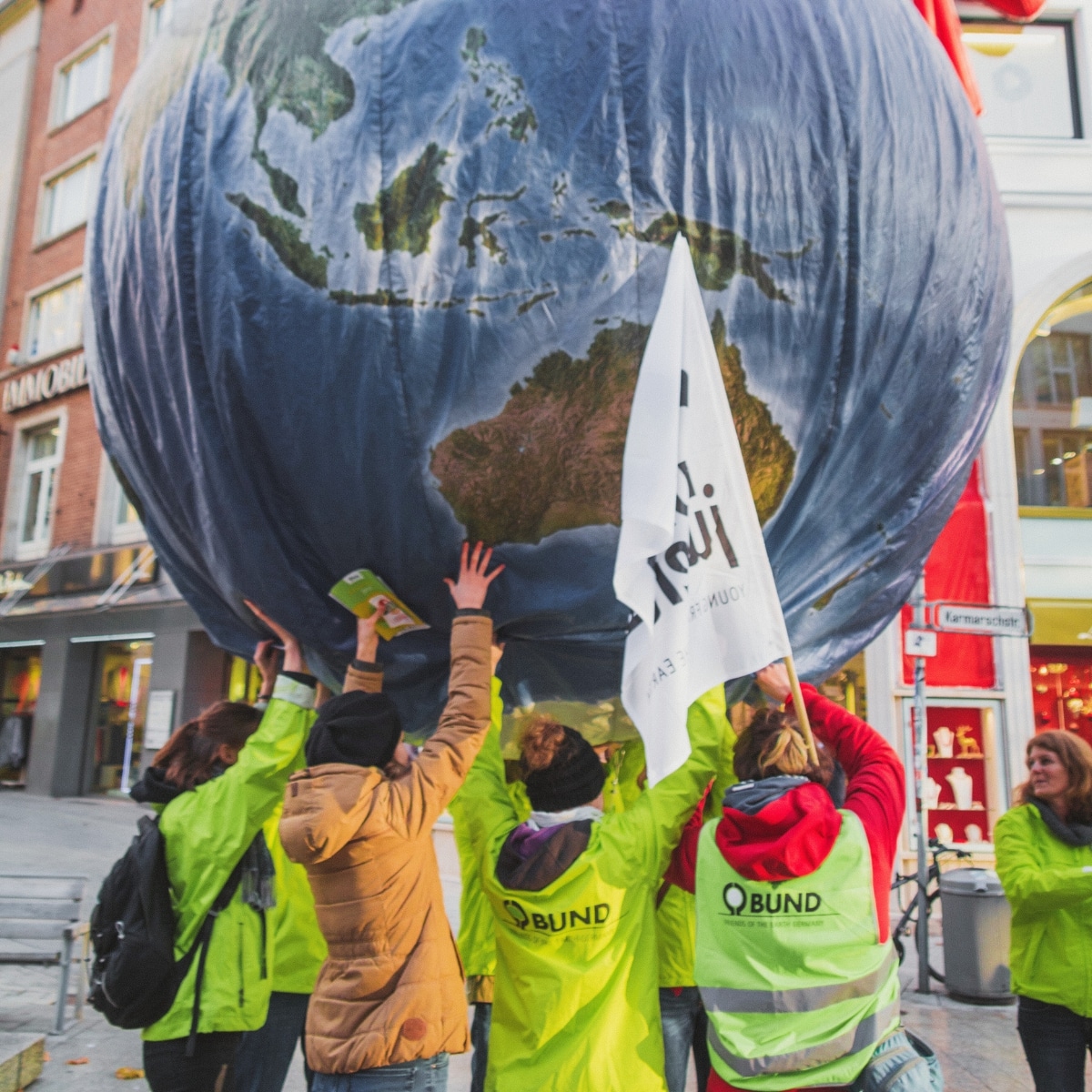 Menschen stützen große Erdkugel bei Demonstration.