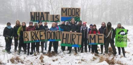 Gruppe hält Schilder im verschneiten Wald.